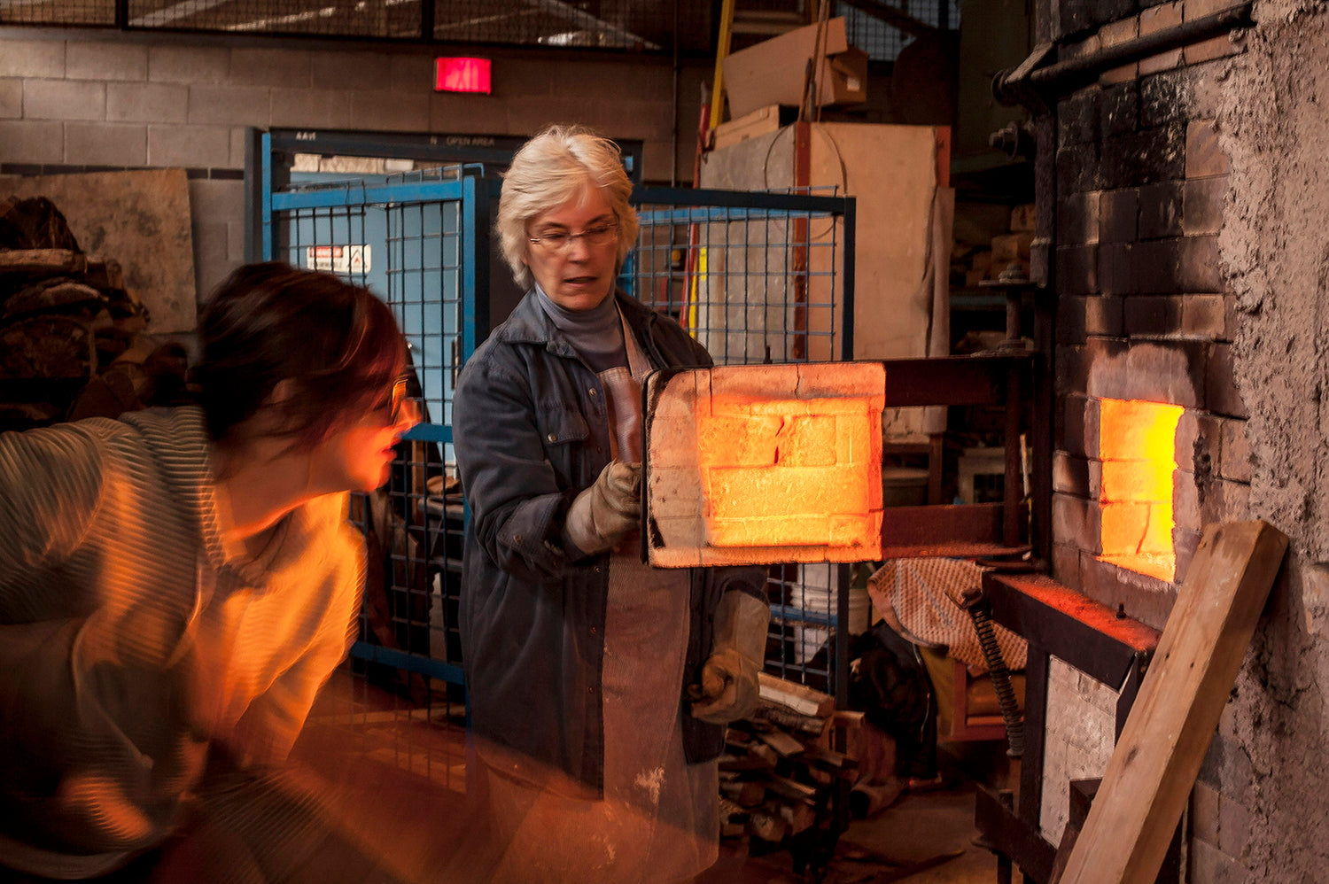 Potter looks into orange-hot kiln ceramic artists are focused and hot photo by Owen Colborne